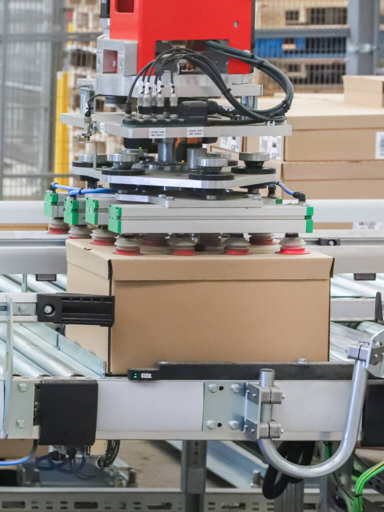 automated box package handling using vacuum suction on roller conveyor