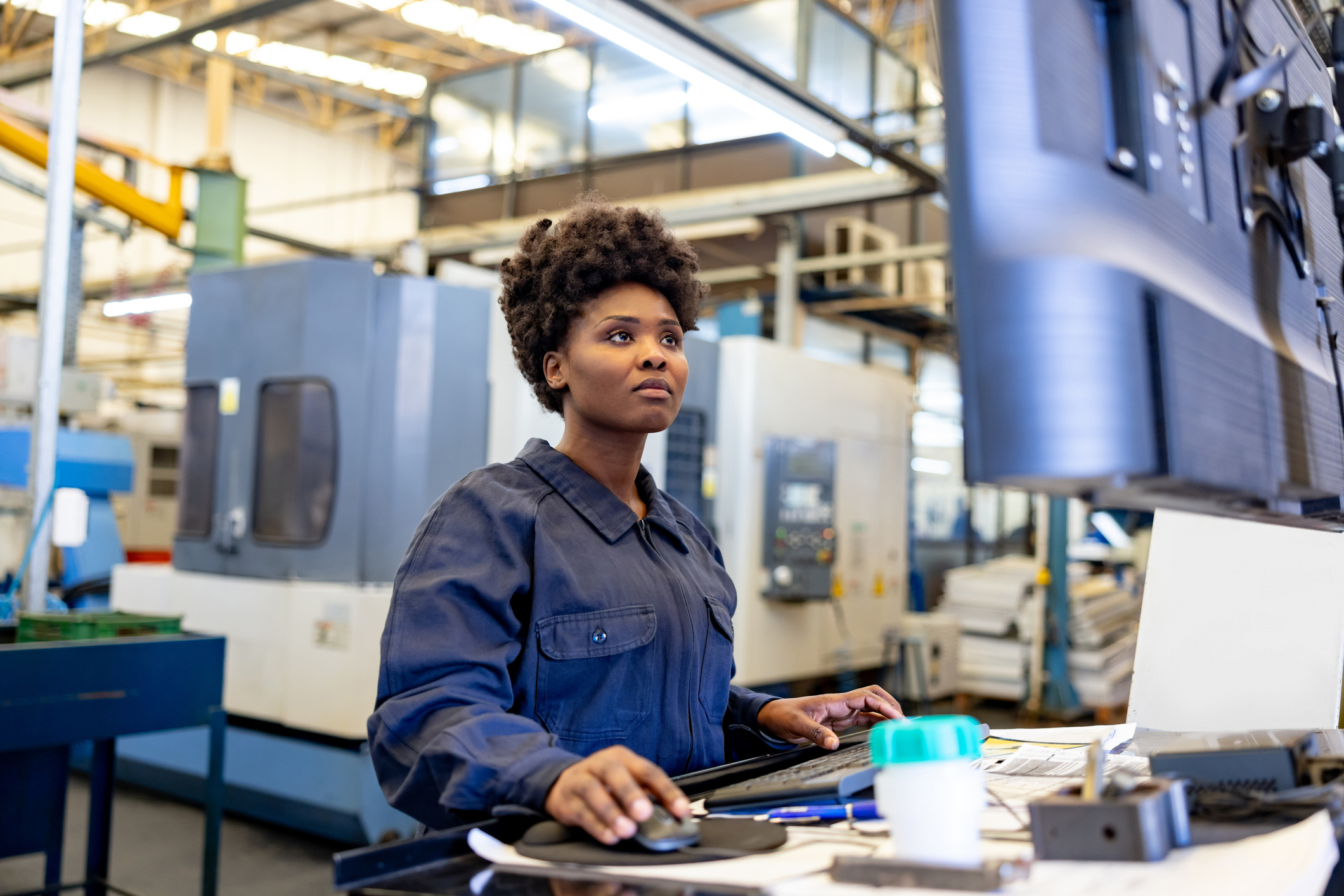 Manufacturing employee operating CNC equipment while monitoring production systems that support AI-ready manufacturing operations.