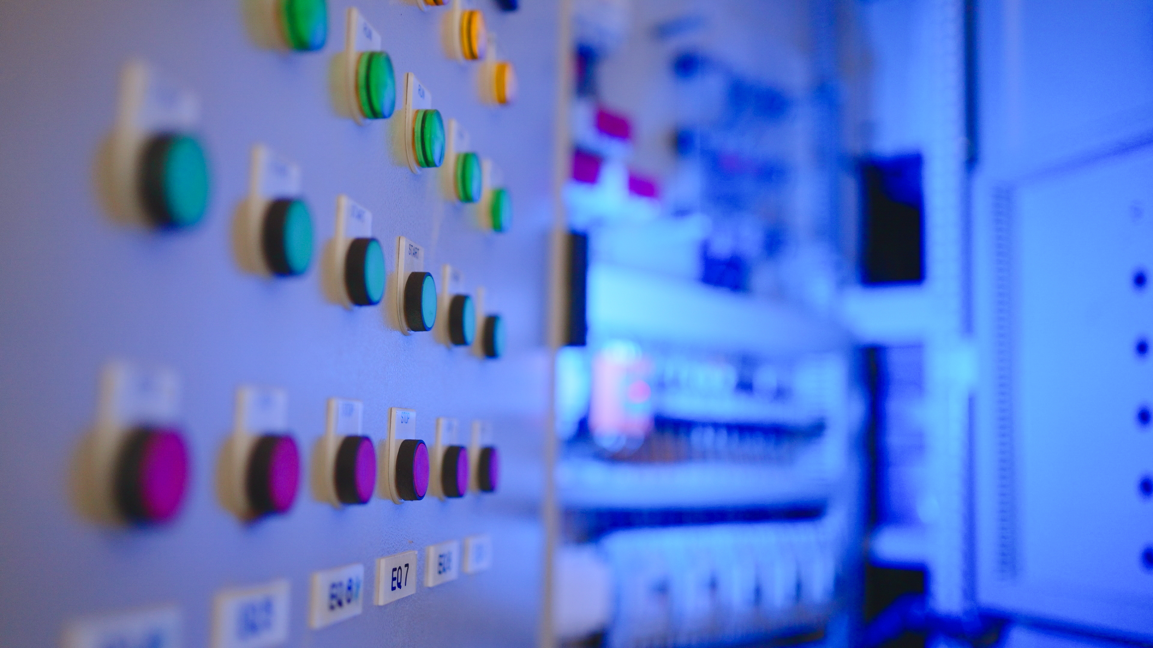 industrial control panel with illuminated push buttons and labeled operator controls inside a modern manufacturing facility