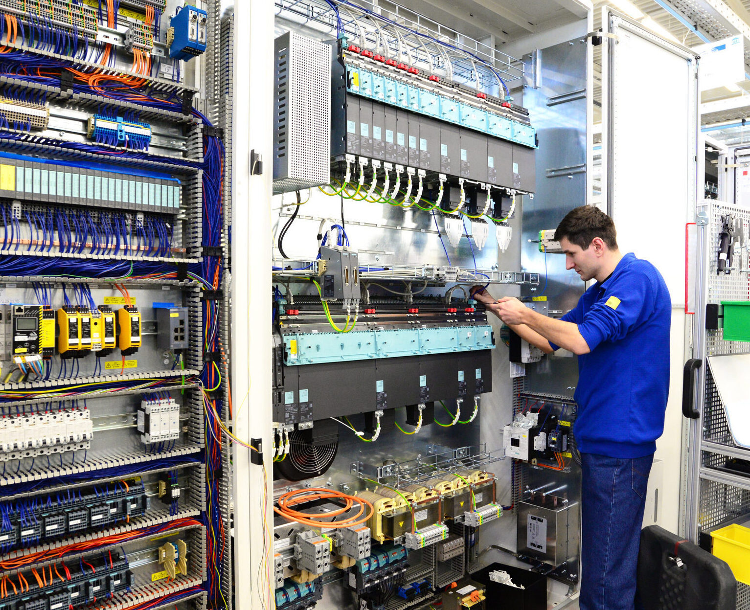 controls engineer inspecting an industrial electrical control panel with PLCs, wiring, and automation components that support manufacturing operations and AI readiness