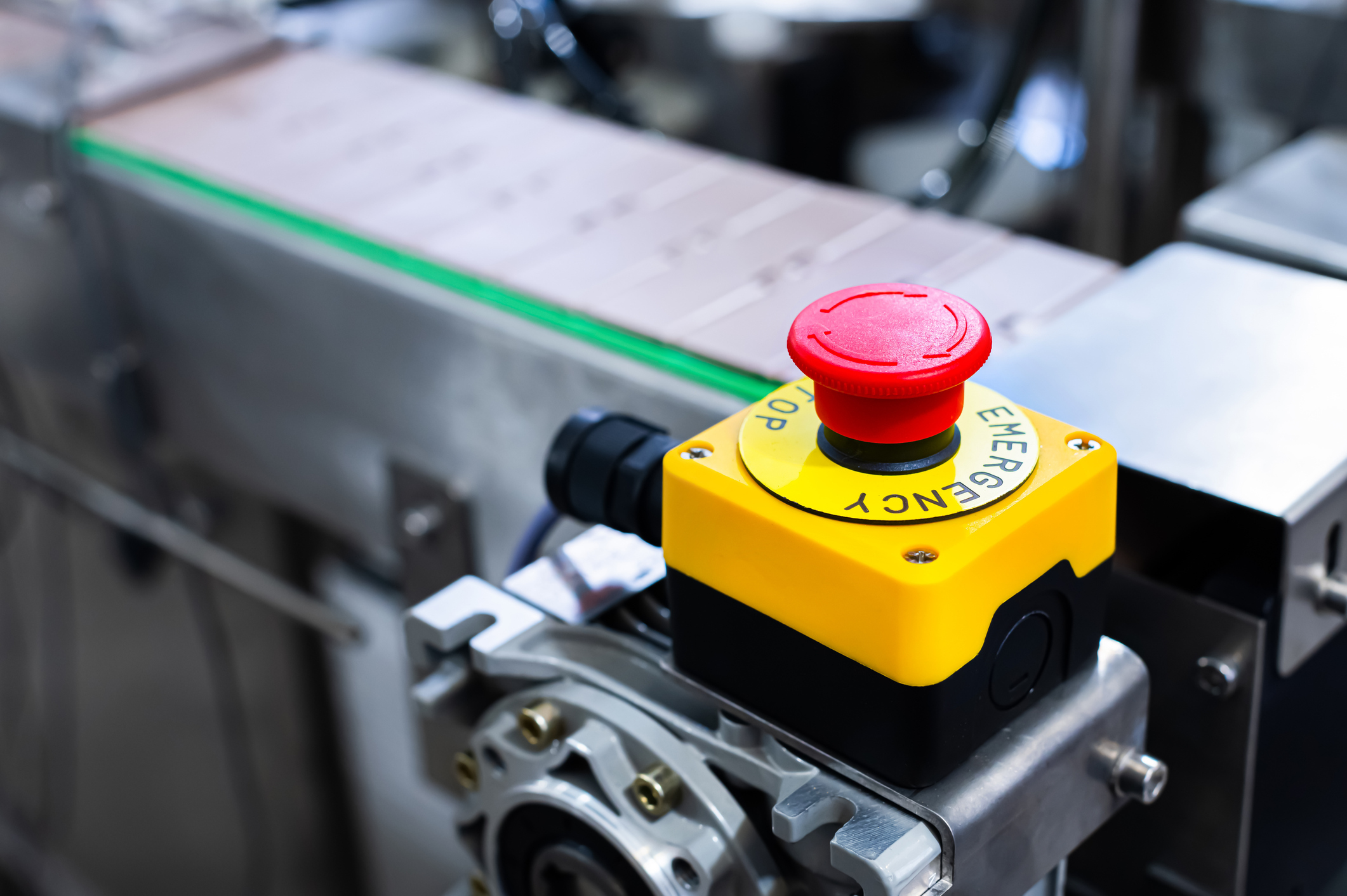 emergency stop button on industrial conveyor system illustrating unplanned downtime risk in automated manufacturing