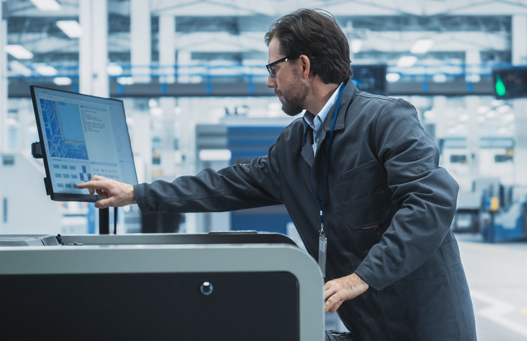 manufacturing worker operating a touchscreen control system on the plant floor, illustrating the technology and operational infrastructure needed to support AI