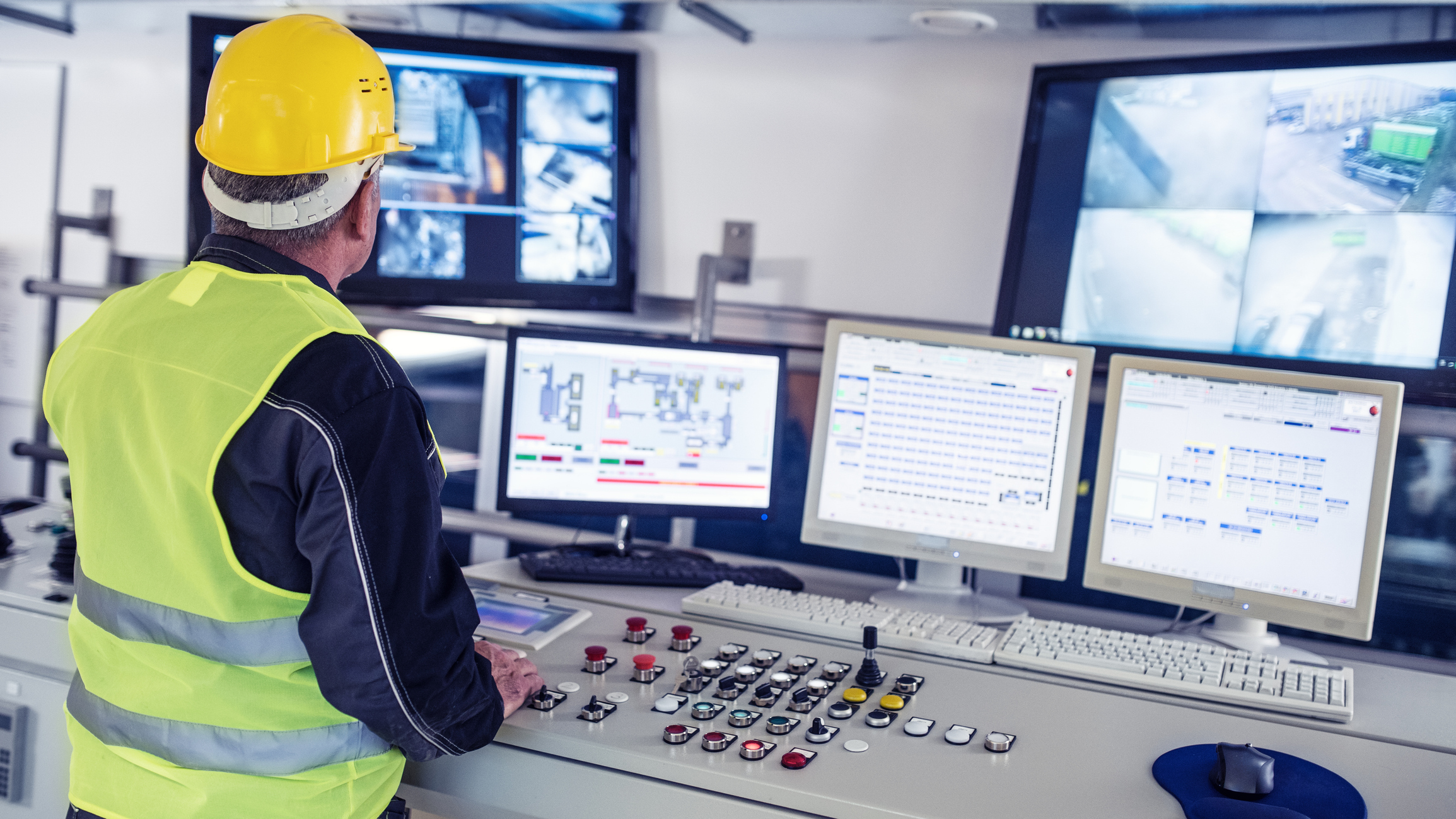 operator in a modern facility monitoring production conditions from a multi-screen control station