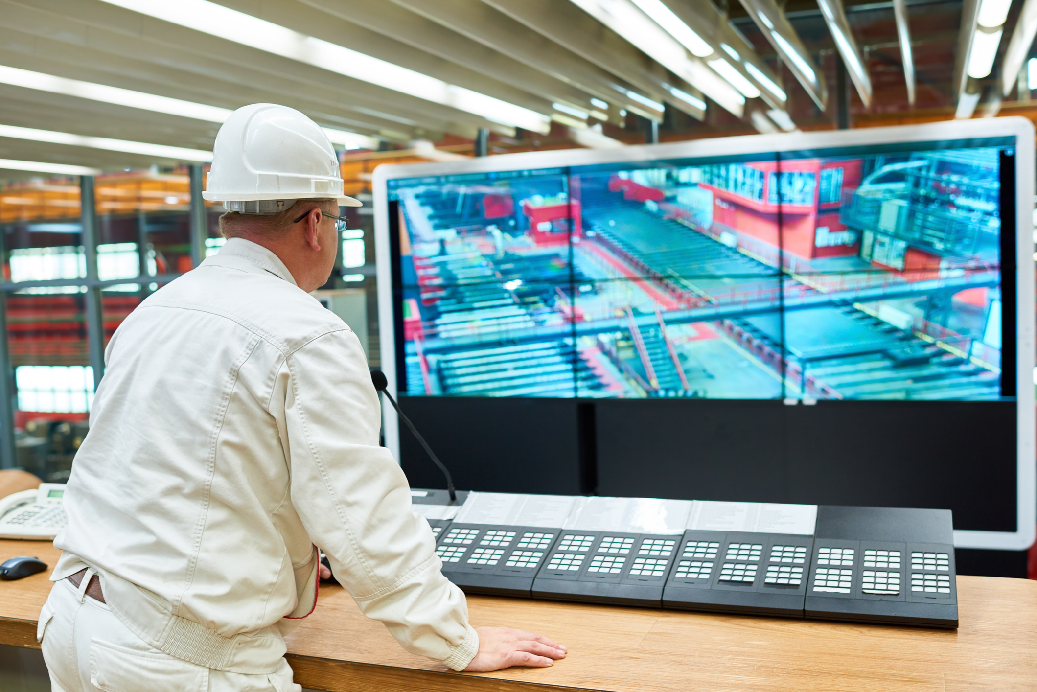 factory operator at a control station watching live production line feeds that show real time activity and equipment status for continuous visibility into operations