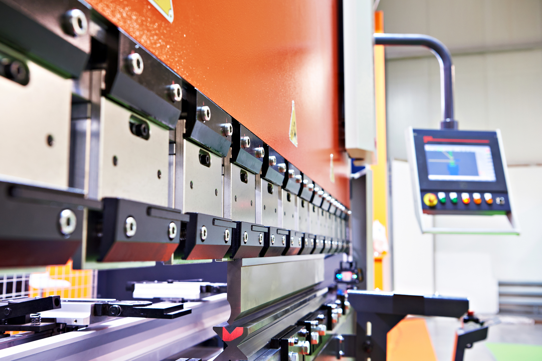 close-up of a press brake with modern controls bending metal, illustrating how aging drives and fragmented diagnostics in heavy industrial operations are replaced by integrated plc, hmi, and centralized monitoring to reduce downtime and improve reliability